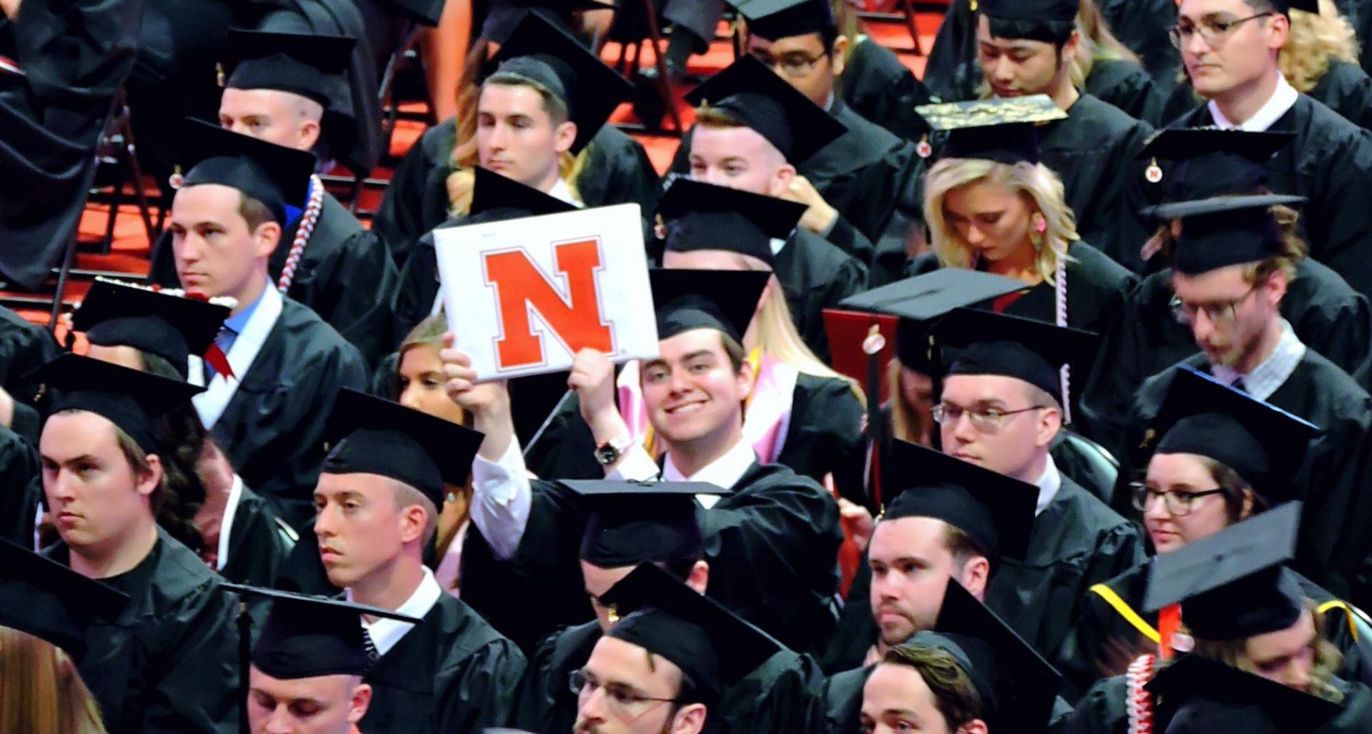 Lawrence Seminario holds up his diploma at UNL graduation.